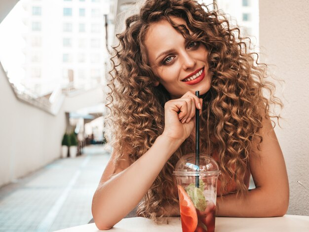 Fille de boire un smoothie frais dans une tasse en plastique avec de la paille