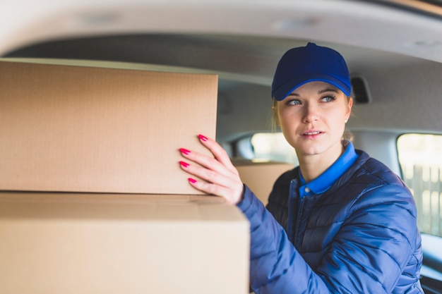 Photo gratuite fille avec des boîtes dans la voiture de livraison