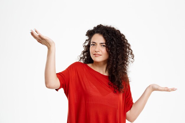 fille bouclée confuse sur mur blanc