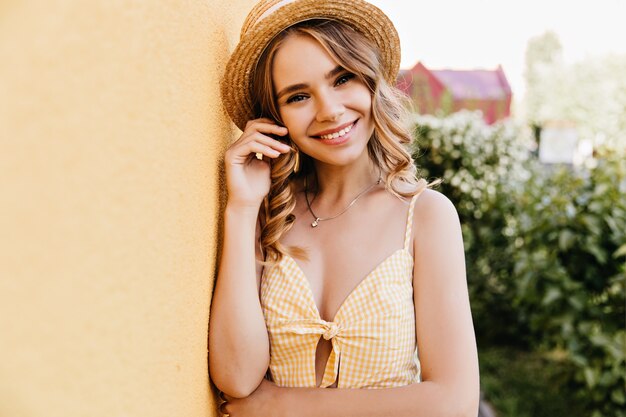 Fille bouclée romantique souriant dans la rue. Blithesome femme caucasienne en tenue jaune posant en plein air.