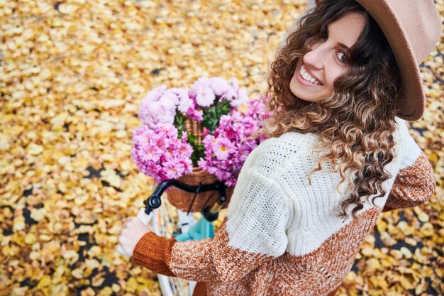 Fille bouclée avec vélo sur fond de feuilles tombées