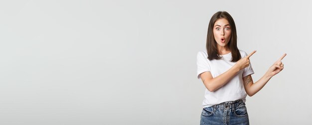 Une fille brune impressionnée et amusée dit wow et pointe le coin supérieur droit sur la bannière