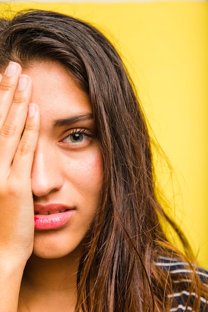 Fille brune avec la main sur le visage