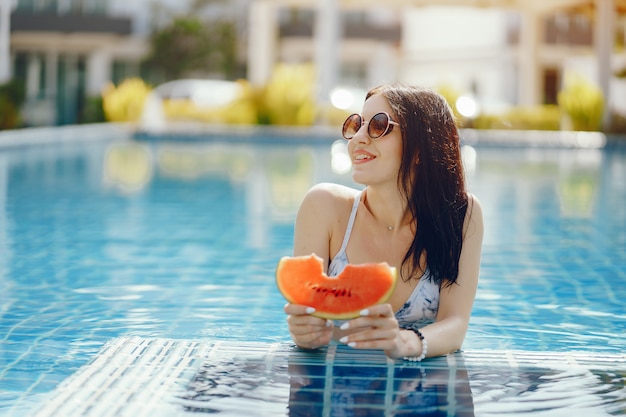 fille brune, manger des fruits au bord de la piscine