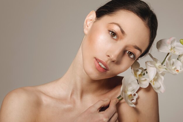 Fille brune posant avec des fleurs