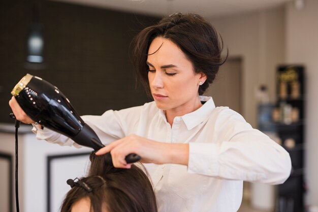 Fille brune se fait sécher les cheveux