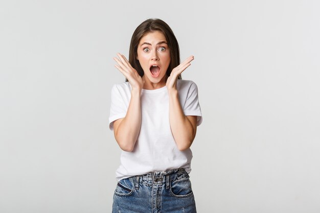 Fille brune surprise et étonnée haletante, la mâchoire tombante impressionnée.