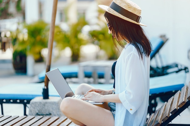 fille brune travaillant sur son ordinateur au bord de la piscine