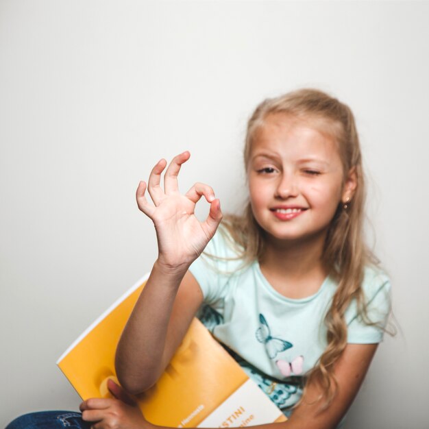 Fille avec un cahier donnant un signe correct