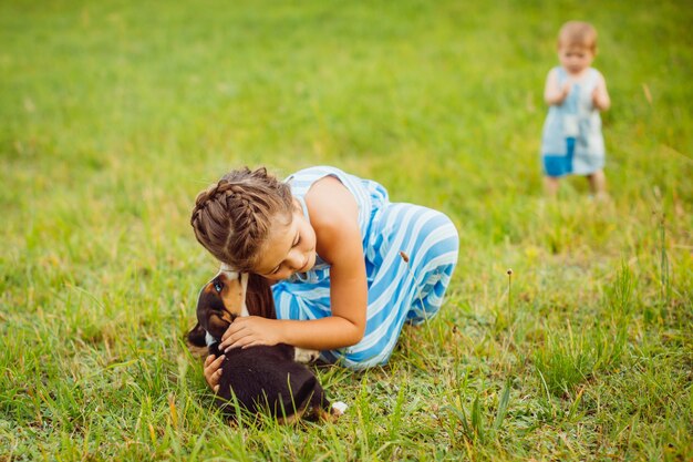 Fille câlins petit chiot assis sur le terrain