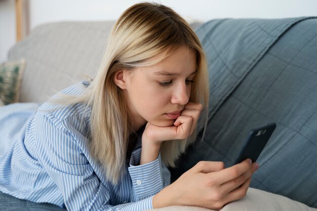 Fille sur le canapé avec vue latérale sur smartphone