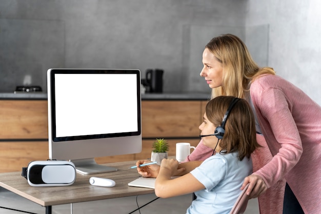 Photo gratuite fille avec casque d'apprentissage en ligne avec sa mère à ses côtés