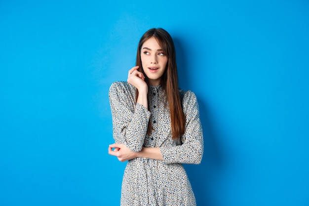 Fille caucasienne pensive avec de longs cheveux naturels vêtue d'une robe vintage à gauche avec une fac réfléchie...