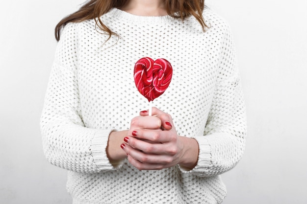 Fille en chandail blanc tenant dans les mains douce et délicieuse lollipop dans t