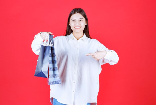 Fille en chemise blanche tenant plusieurs sacs à provisions