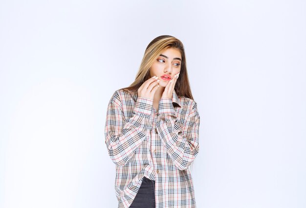 La fille en chemise à carreaux a l'air réfléchie et douteuse