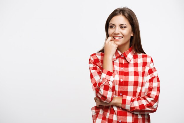 Fille en chemise à carreaux posant avec la main droite sur la joue