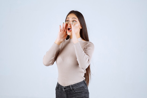 Fille en chemise grise criant à haute voix.