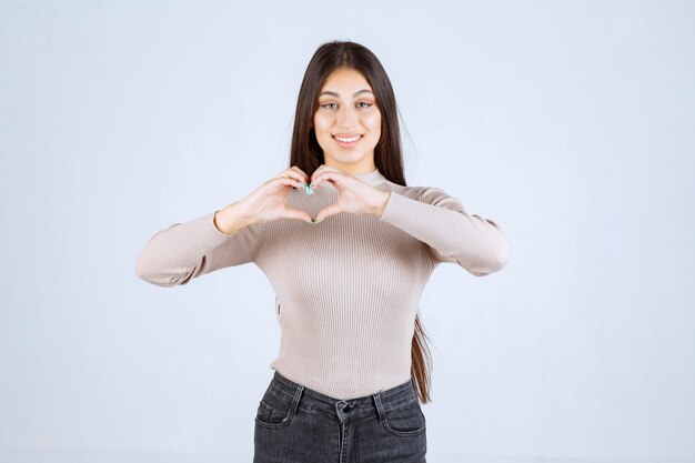 Fille en chemise grise envoyant l'amour à ses fans.