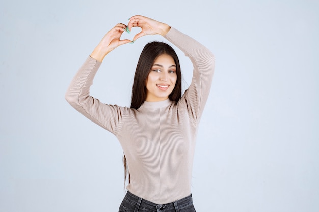 Fille en chemise grise envoyant l'amour à ses fans.