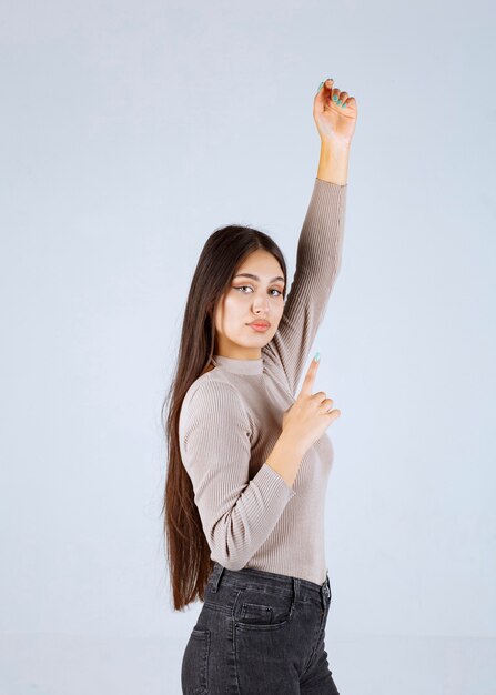 Fille en chemise grise levant les mains.