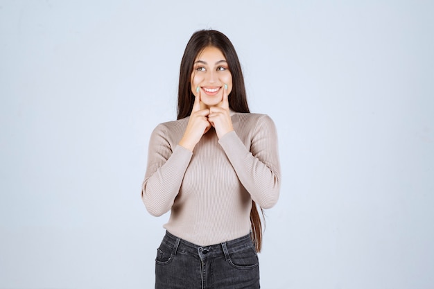 Fille en chemise grise pointant sa tête et pensant.