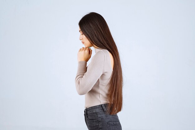 Fille en chemise grise rêvant de quelque chose.