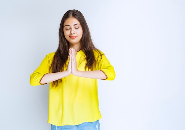 Fille en chemise jaune unissant les mains et rêvant.