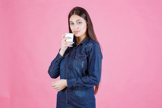 Fille en chemise en jean, boire une tasse de café