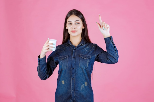 Fille en chemise en jean tenant une tasse de café et de la pensée