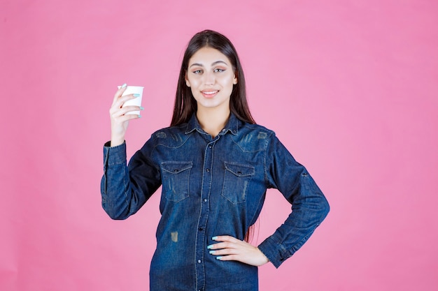 Fille en chemise en jean tenant une tasse de café et se sent positif