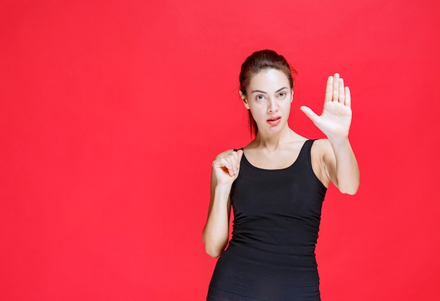 Fille en chemise noire essayant d'empêcher le danger de venir à elle. photo de haute qualité