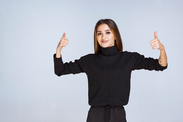 Fille en chemise noire montrant un signe positif de la main. photo de haute qualité