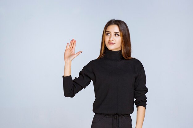 Fille en chemise noire s'arrêtant et empêchant quelque chose. photo de haute qualité