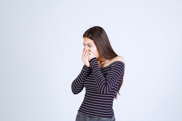 Fille en chemise rayée demandant le silence.