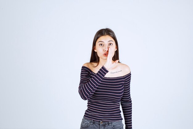 Fille en chemise rayée écoutant ou faisant des potins.