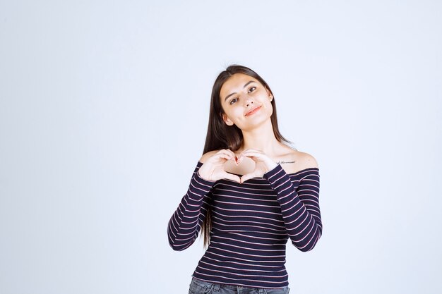 Fille en chemise rayée envoyant l'amour.