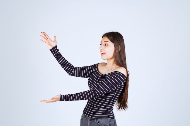 Fille en chemise rayée montrant la mesure ou la quantité estimée d'un produit.