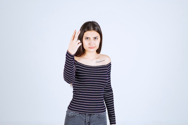 Fille en chemise rayée pointant vers le haut et montrant des émotions.