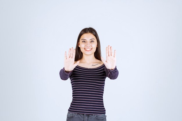 Fille en chemise rayée s'arrêtant et empêchant quelque chose.