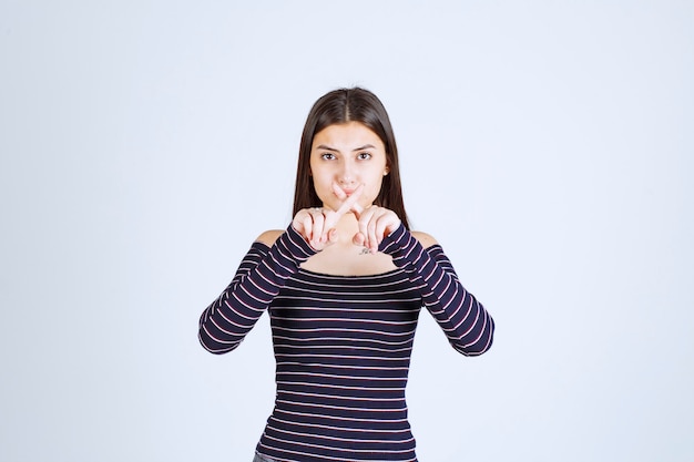 Photo gratuite fille en chemise rayée s'arrêtant et empêchant quelque chose.