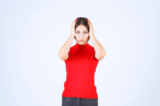 Une fille en chemise rouge a l'air effrayée et terrifiée.