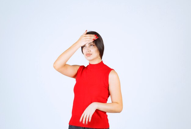 La fille en chemise rouge a l'air fatiguée et endormie.