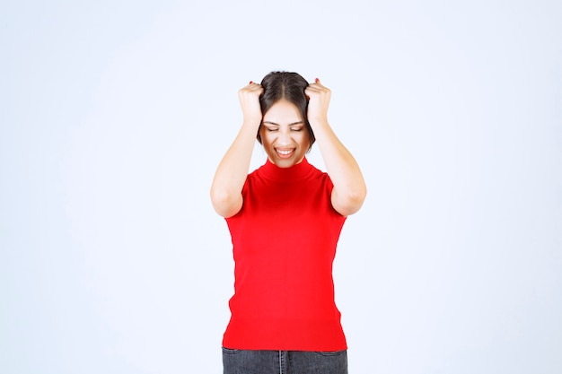 La fille en chemise rouge a l'air stressée et nerveuse.