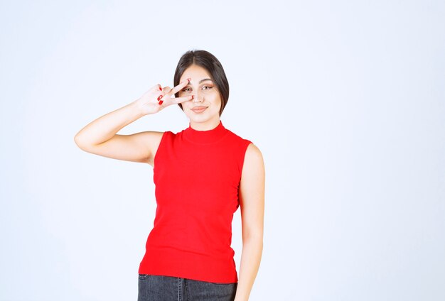 Une fille en chemise rouge fait un clin d'œil et montre sa satisfaction.