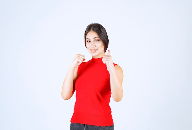 Fille en chemise rouge montrant le signe de la main de plaisir.