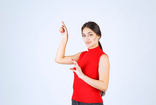 Fille en chemise rouge montrant un signe positif de la main.