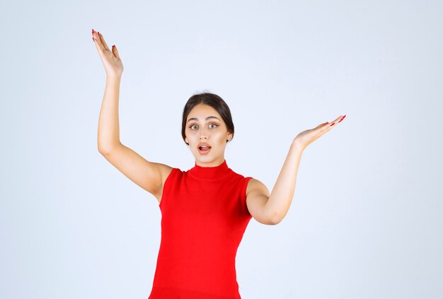 Fille en chemise rouge pointant des deux côtés.