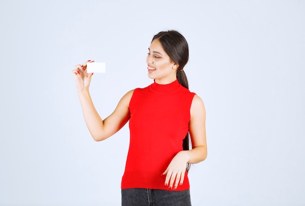 Fille en chemise rouge présentant sa carte de visite.