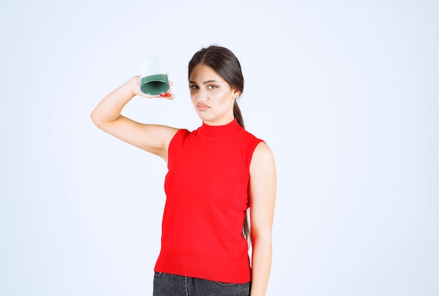 Fille En Chemise Rouge Tenant Une Tasse à L'envers.